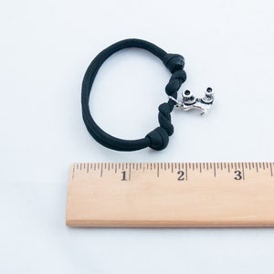 May include: Black paracord bracelet with a silver roller skate charm. The bracelet is approximately 2 inches in length.
