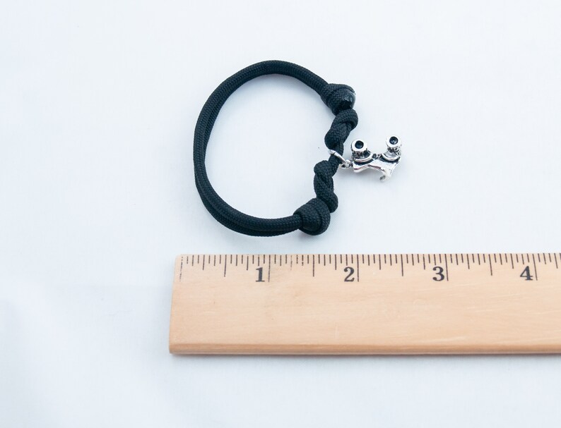 May include: Black paracord bracelet with a silver roller skate charm. The bracelet is approximately 2 inches in length.
