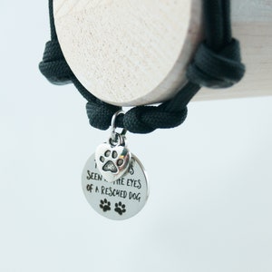 May include: A black paracord bracelet with a silver charm that says "I've seen the eyes of a rescued dog". The charm also has a small paw print heart.
