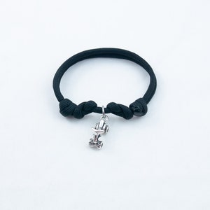 May include: A black paracord bracelet with a silver charm of a race car.