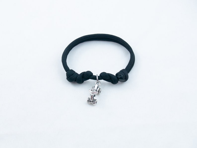 May include: A black paracord bracelet with a silver charm of a race car.