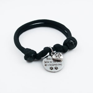 May include: Black paracord bracelet with a silver charm that reads "True love is seen in the eyes of a rescued dog" with a paw print heart.