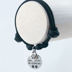 May include: Black paracord bracelet with a silver charm that says "I've seen into the eyes of a rescued dog". The charm has a paw print on it.