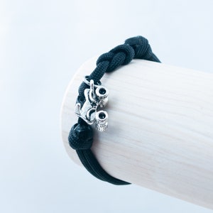 May include: Black paracord bracelet with a silver roller skate charm.