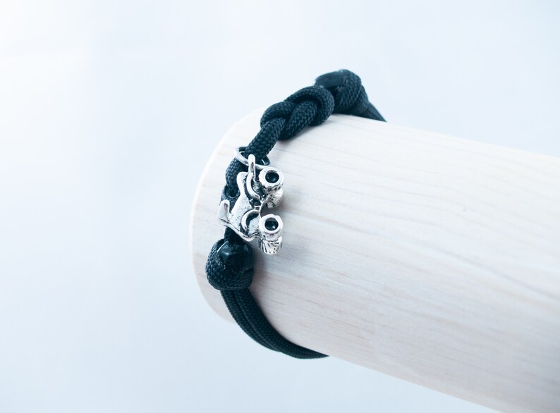 May include: Black paracord bracelet with a silver roller skate charm.