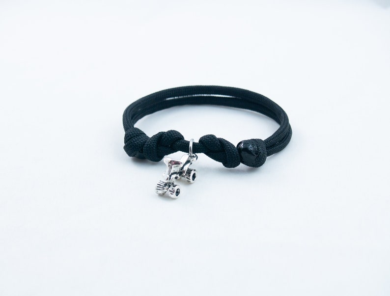 May include: A black paracord bracelet with a silver roller skate charm.