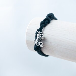 May include: Black paracord bracelet with a silver monster truck charm.