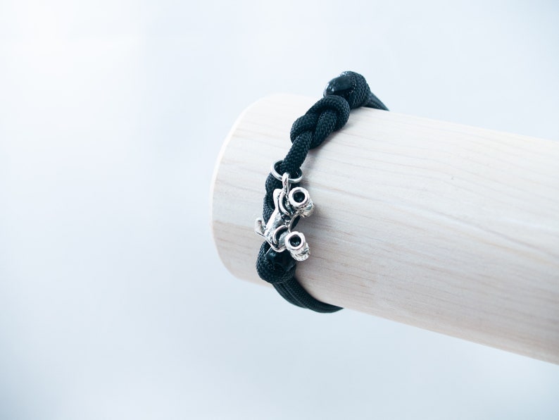 May include: Black paracord bracelet with a silver monster truck charm.