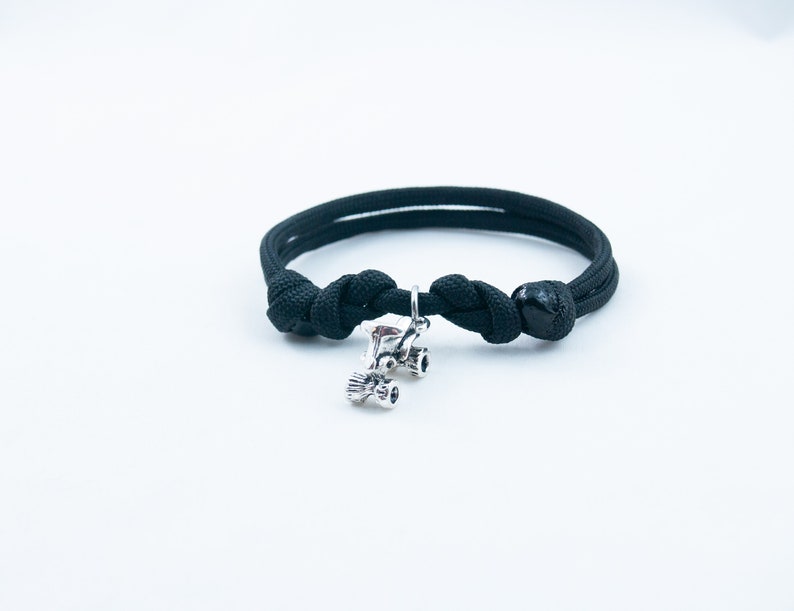 May include: A black paracord bracelet with a silver charm of a roller skate.