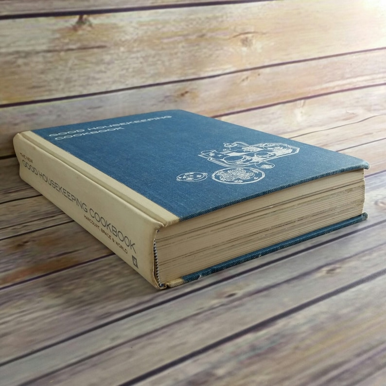 May include: A blue hardcover cookbook titled "Good Housekeeping Cookbook" with a white illustration of a table setting on the cover.