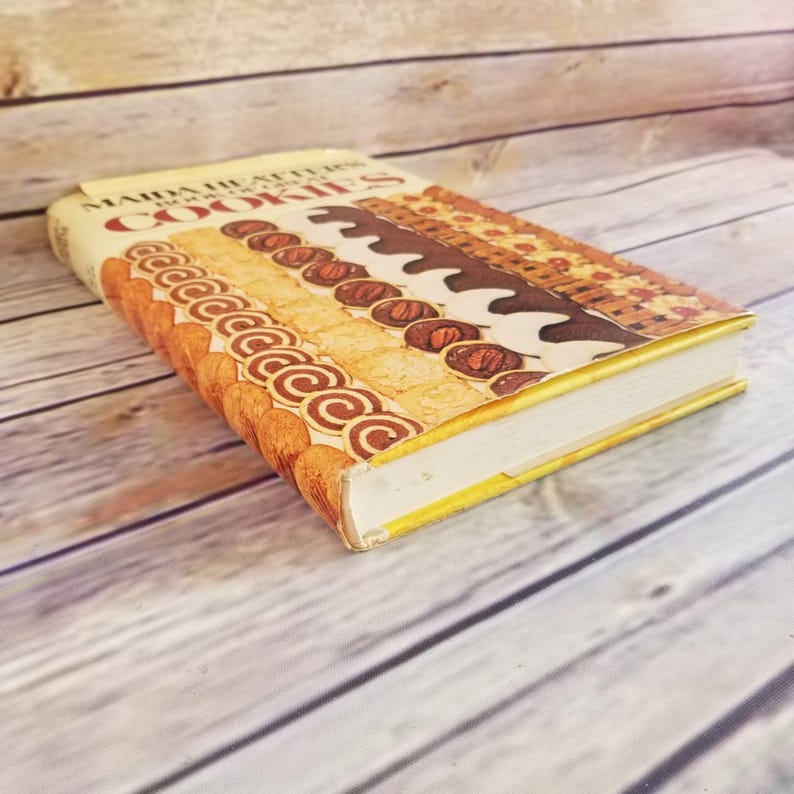 Pode incluir: Um livro de receitas vintage intitulado "Martha Stewart's Cookies" com uma capa colorida que apresenta uma variedade de biscoitos e sobremesas.