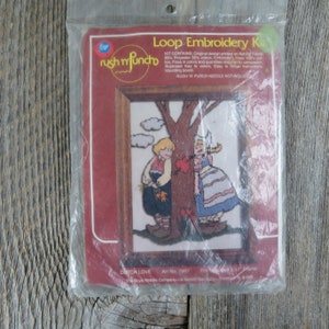 May include: A vintage Rush 'n Punch loop embroidery kit featuring a Dutch love scene. The kit includes floss, a mounting board, and instructions. The kit is packaged in a clear plastic bag with a red and white label. The label reads "Loop Embroidery Kit" and "Dutch Love Art No. 7007".