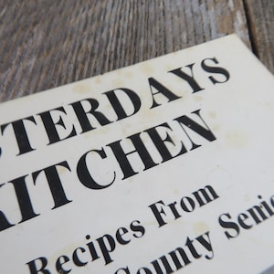 May include: Close-up of a white book cover with the title "Yesterday's Kitchen" in black bold letters. The text "Recipes From County Senior" is also visible in black letters.