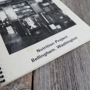 May include: Black and white photo of a room with shelves and a chair. The photo is from a book titled "Nutrition Project Bellingham, Washington."