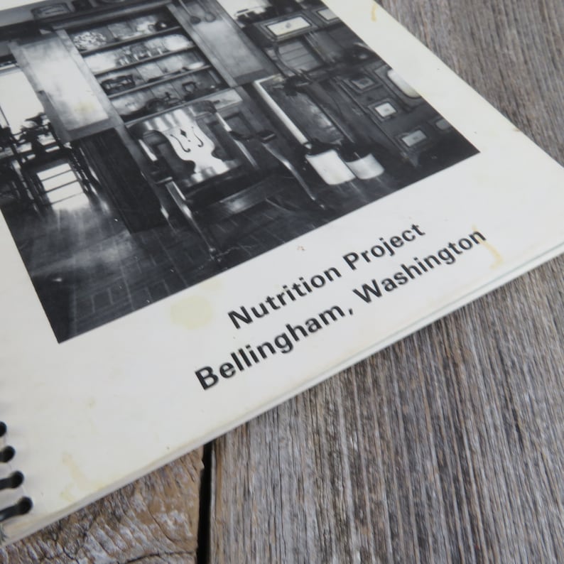 May include: Black and white photo of a room with shelves and a chair. The photo is from a book titled "Nutrition Project Bellingham, Washington."