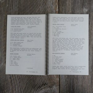 May include: A vintage cookbook with a brown leather cover and gold spiral binding. The pages contain handwritten recipes for various cookies, including peanut blossoms, almond bark drop cookies, little hay stacks, rice krispies cookies, and Danish sugar cookies.