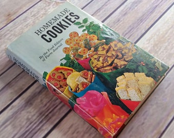 Könnte beinhalten: Ein Vintage-Kochbuch mit dem Titel "Homemade Cookies" von den Food Editoren des Farm Journal. Der Umschlag zeigt eine farbenfrohe Illustration verschiedener Kekse in festlicher Weihnachtsverpackung.