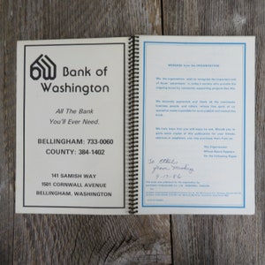 May include: A white and blue booklet with the title "Bank of Washington" and the text "All The Bank You'll Ever Need." The booklet also includes the phone numbers for Bellingham and County. The booklet is open to a page with a message from the organization and a handwritten note that says "To Ethel from Mickey 9-17-86".