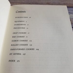 Pode incluir: Um livro intitulado "Cookies" com uma tabela de conte&uacute;do listando diferentes tipos de biscoitos, incluindo biscoitos de gota, biscoitos de barra, biscoitos de geladeira, biscoitos enrolados, biscoitos moldados &agrave; m&atilde;o e etc. O livro tamb&eacute;m inclui um &iacute;ndice.