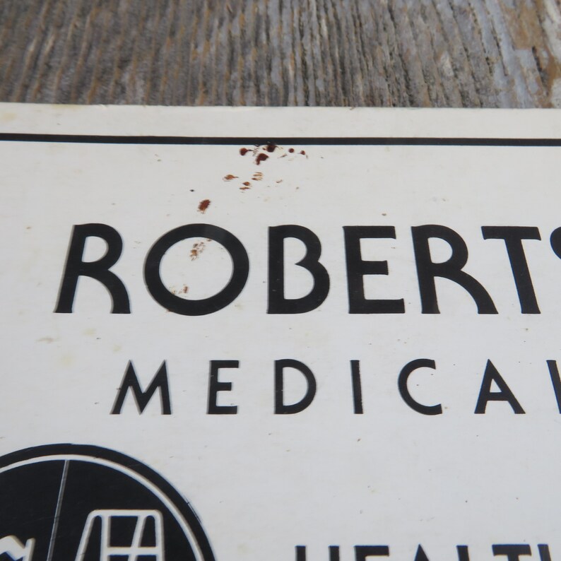 May include: A white sign with black text that reads "ROBERTS MEDICAL" with a black and white logo of a medical symbol below the text.
