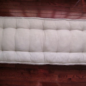 May include: A white and gray striped mattress topper with tufted buttons. The topper is made of a soft, comfortable fabric and is perfect for adding extra padding to a bed.