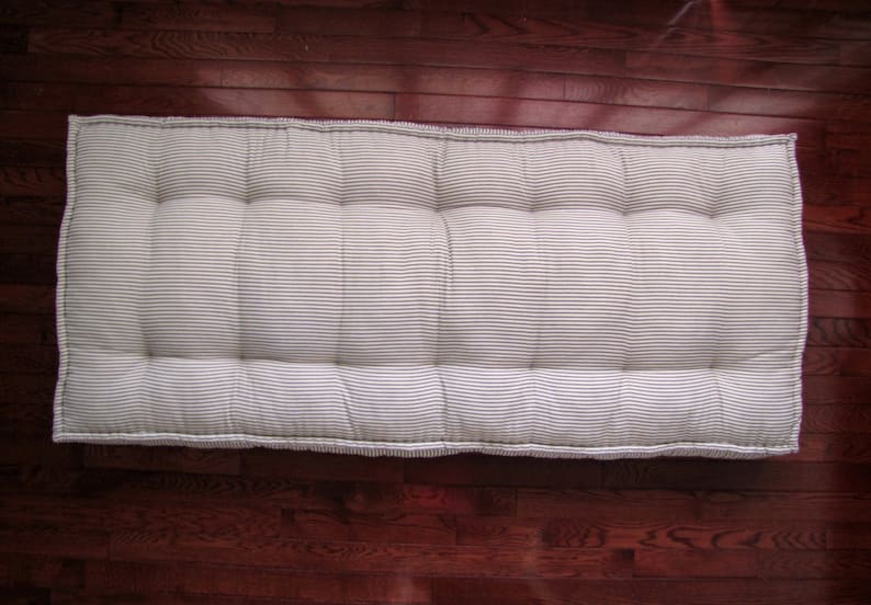 May include: A white and gray striped mattress topper with tufted buttons. The topper is made of a soft, comfortable fabric and is perfect for adding extra padding to a bed.