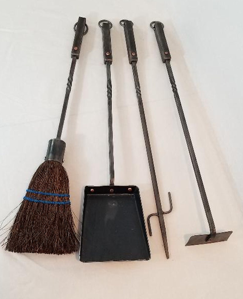 Pu&ograve; includere: Un set di quattro strumenti per camino con manici in metallo ritorto. Gli strumenti includono una spazzola, una pala, un attizzatoio e una pinza. Gli strumenti sono in metallo nero e hanno dettagli in rame.