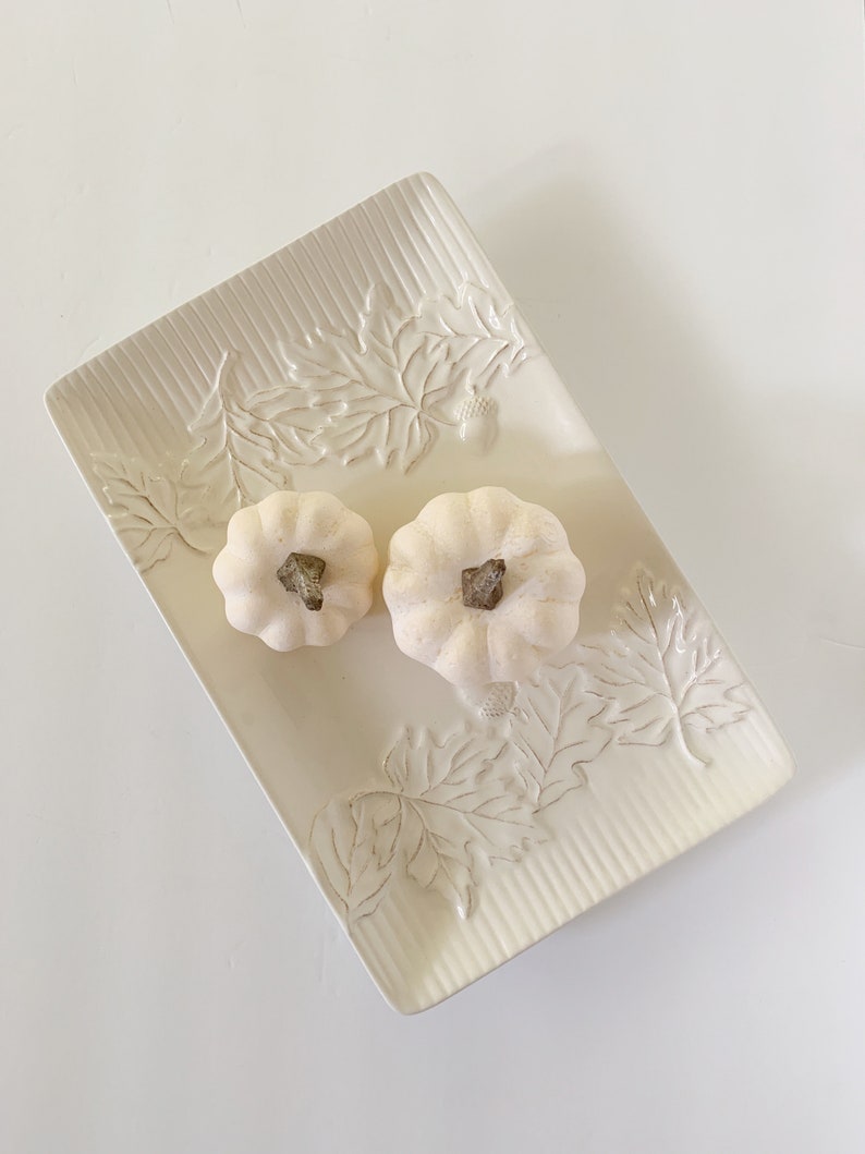 May include: White ceramic serving tray with an embossed leaf design. Two small white pumpkins are on the tray.