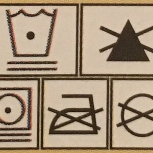 May include: A set of four black and white laundry care symbols. The first symbol is a tub of water with three horizontal lines underneath. The second symbol is a triangle with three horizontal lines extending from each side. The third symbol is a circle with a dot in the center and three horizontal lines underneath. The fourth symbol is a crossed-out iron with a horizontal line underneath.