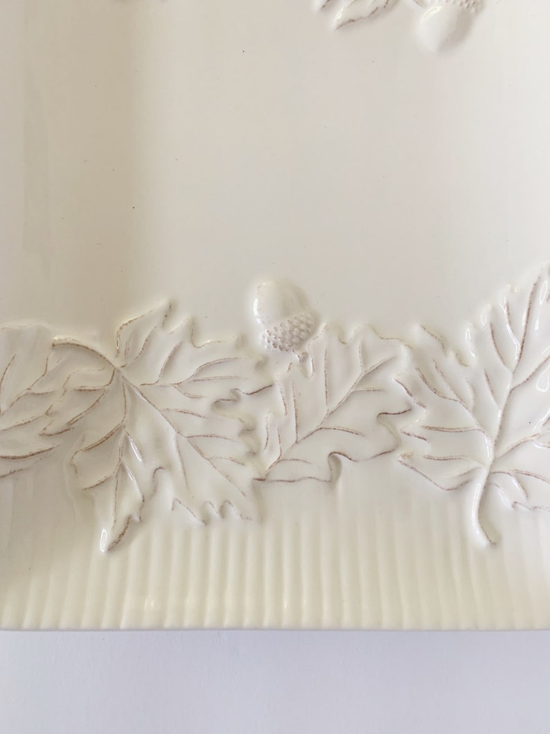 May include: White ceramic serving tray with a raised design of leaves and acorns around the edge.
