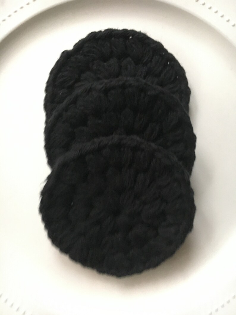 May include: Three black crocheted makeup remover pads stacked on top of each other.