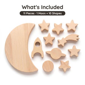 Pu&ograve; includere: Un set di 11 pezzi in legno di colore chiaro che include una grande luna crescente e dieci forme a tema spaziale: un razzo, un pianeta con anelli, una stella cadente e sette stelle. Il testo "What's Included" e "11 Pieces &middot; 1 Moon + 10 Shapes" &egrave; visibile.