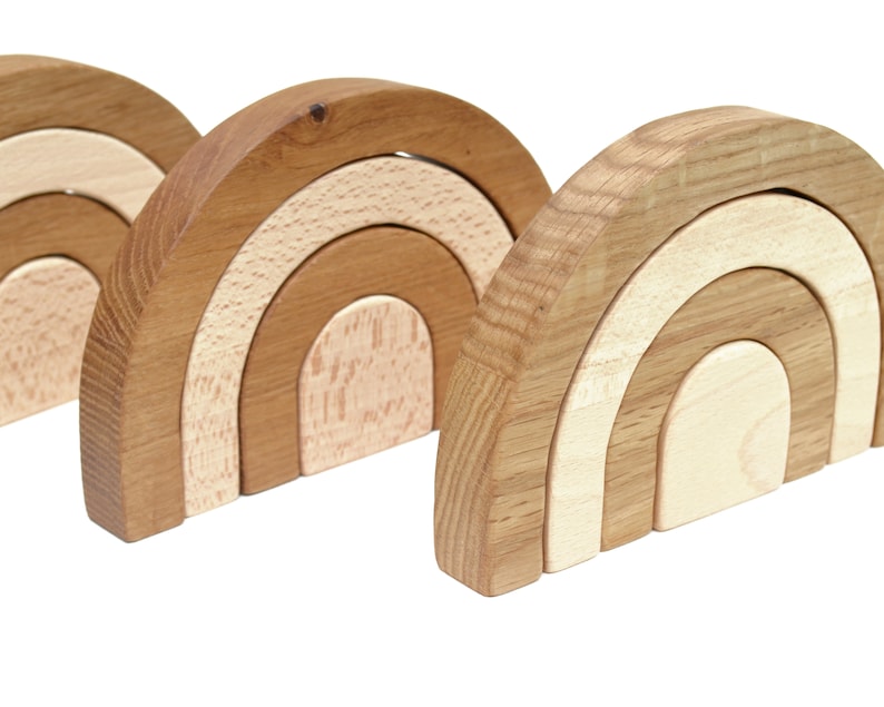 May include: Three wooden rainbow arches, each with three layers of different shades of brown and beige. The arches are stacked on top of each other, creating a cascading effect.