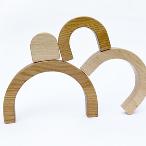 May include: Wooden arch-shaped blocks stacked on top of each other. The blocks are made of natural wood and have a smooth finish.