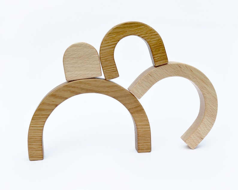 May include: Wooden arch-shaped blocks stacked on top of each other. The blocks are made of natural wood and have a smooth finish.