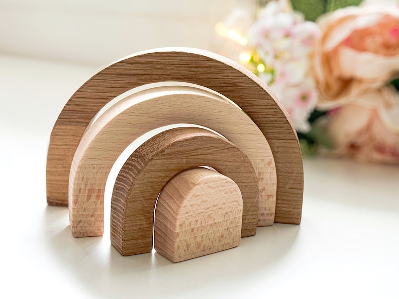 May include: A set of four wooden rainbow arches, nested together in decreasing size. The arches are made of natural wood and have a smooth, polished finish.