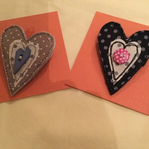 May include: Two fabric heart-shaped ornaments with polka dot patterns and buttons. The hearts are layered and stitched together.
