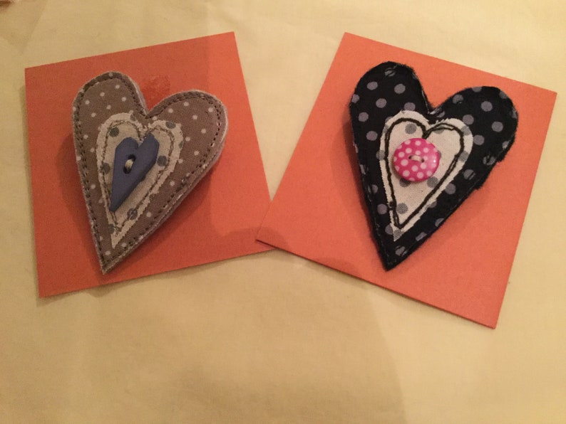 May include: Two fabric heart-shaped ornaments with polka dot patterns and buttons. The hearts are layered and stitched together.