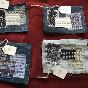 Könnte beinhalten: Vier kleine Stoffquadrate, jedes mit einem anderen Patchwork-Design, werden auf einer roten Oberfläche angezeigt. Jedes Quadrat hat ein weißes Etikett mit einem Buchstaben darauf: P, Q, R und S.