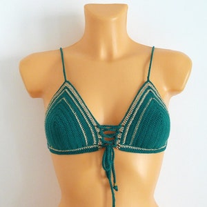 Op de afbeelding: Teal gehaakte bikinitop met een driehoekig ontwerp. De top heeft dunne spaghettibandjes en een veter aan de voorkant met goudkleurige kralen. De randen zijn afgewerkt met een lichtbeige kleur.