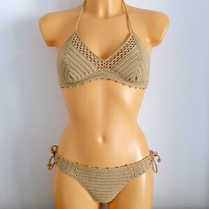 Peut inclure: Un haut et un bas de bikini en crochet beige. Le haut est de style halter avec une forme triangulaire. Le bas est de style taille haute avec des liens sur les c&ocirc;t&eacute;s.