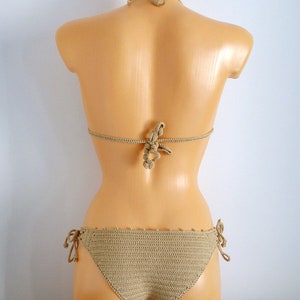 Peut inclure: Un haut et un bas de bikini en crochet beige avec une fermeture &agrave; nouer sur les c&ocirc;t&eacute;s. Le bikini est sur un mannequin blanc.
