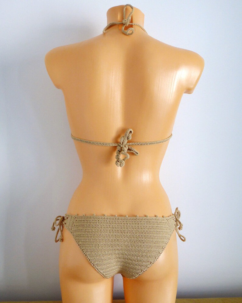 Peut inclure: Un haut et un bas de bikini en crochet beige avec une fermeture &agrave; nouer sur les c&ocirc;t&eacute;s. Le bikini est sur un mannequin blanc.