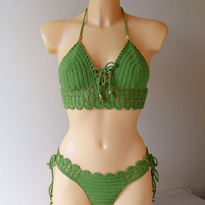 May include: Green crochet bikini top and bottom with gold beads. The top has a halter style and ties in the front. The bottom has a high-cut leg and ties on the sides.