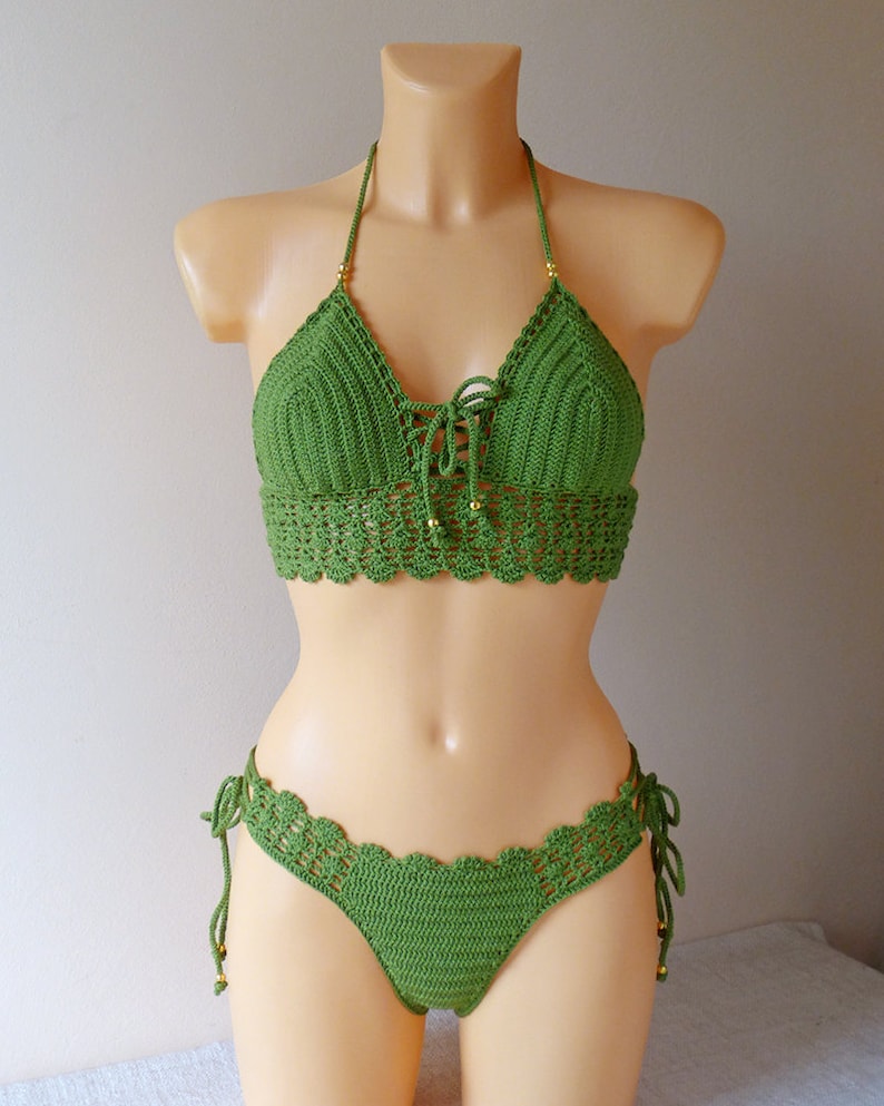 May include: Green crochet bikini top and bottom with gold beads. The top has a halter style and ties in the front. The bottom has a high-cut leg and ties on the sides.