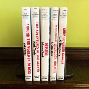 May include: A set of five classic literature books with white covers and red titles. The books are arranged vertically on a wooden shelf. The titles are "Around the World in 80 Days", "The Adventures of Tom Sawyer", "Heidi", "The Adventures of Sherlock Holmes", and "Anne of Green Gables".