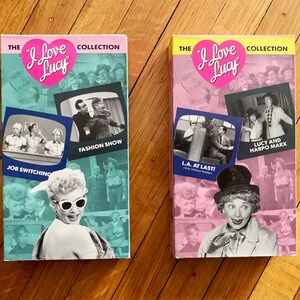 May include: Two VHS tapes of the "I Love Lucy" television show. The tapes are pink and blue with images of Lucille Ball and other characters from the show. The titles of the tapes are "Job Switching" and "L.A. At Last!" The tapes are part of "The I Love Lucy Collection."