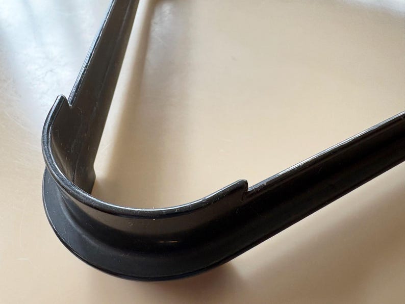 K&ouml;nnte beinhalten: Ein schwarzer, dreieckiger Ausstecher mit abgerundeter Ecke und gezackten Kanten. Der Ausstecher ist aus Metall und liegt auf einer hellen Oberfl&auml;che.