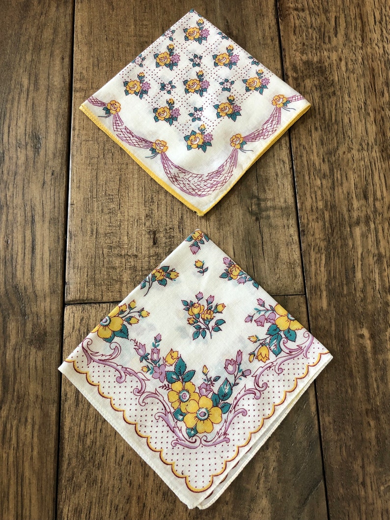 K&ouml;nnte beinhalten: Zwei Vintage-Taschent&uuml;cher mit Blumenmustern. Eines zeigt gelbe Rosen und ein lila Schleifendesign auf wei&szlig;em Hintergrund mit gelbem Rand. Das andere hat gelbe und lila Blumen mit einem gewellten Rand.
