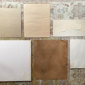 May include: A collection of eight blank, white, rectangular picture frames of various sizes, arranged in a semi-circle on a patterned rug.